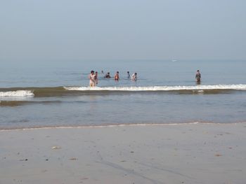 People on beach against clear sky