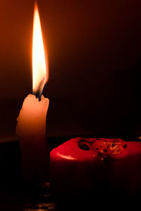 Close-up of lit candle in darkroom