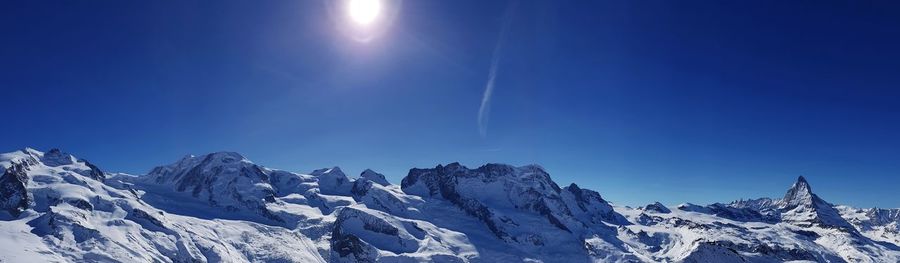 Scenic view of snowcapped mountains against clear blue sky