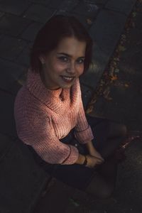 Portrait of a smiling young woman sitting outdoors