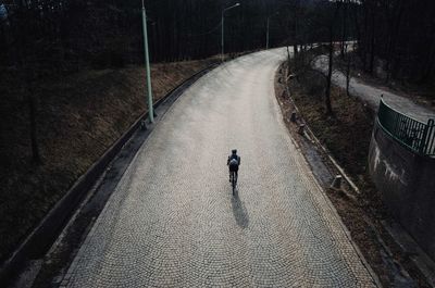 Rear view of man riding cycle on road