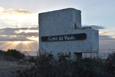 Information sign on land against sky during sunset