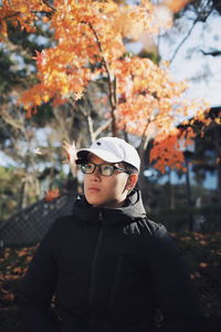 Portrait of young man standing on autumn leaves