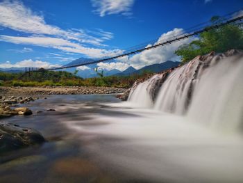 Scenic view of waterfall against sky