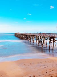 Wooden posts on beach against sky