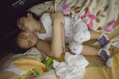 Cute girl with mother sleeping on bed at home