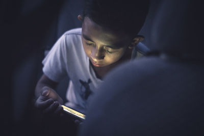 Close-up of boy using smart phone at night