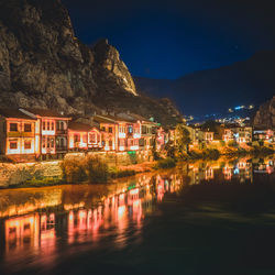 River by illuminated buildings against sky at night