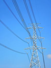 Low angle view of electricity pylon against clear blue sky