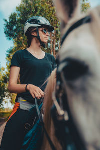 Woman wearing sunglasses and helmet riding horse 