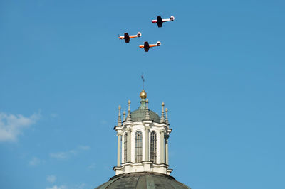 Low angle view of birds flying against blue sky