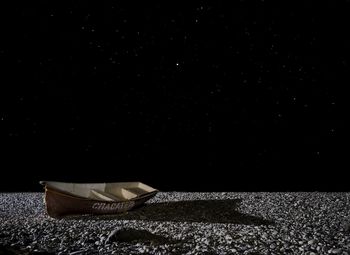 Boat on stones against sky at night