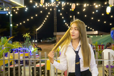 Student wearing uniform while standing in city at night