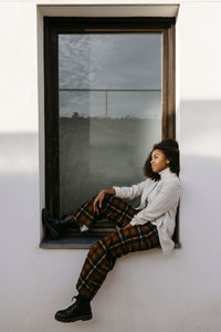 Thoughtful afro young woman sitting on window sill