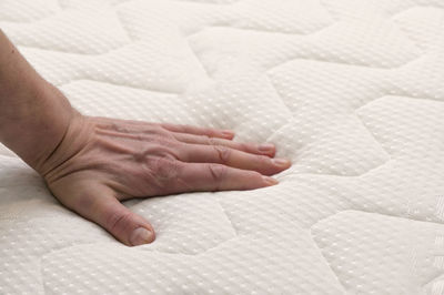 Close-up of human hand on bed