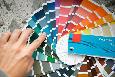 Cropped hand of woman holding multi colored umbrella