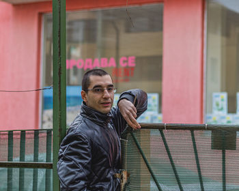 Portrait of young man standing against brick wall