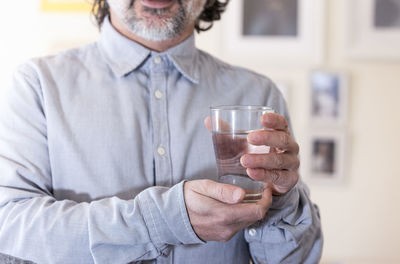 Smiling man holding a glass of water at home. healthy life concept person