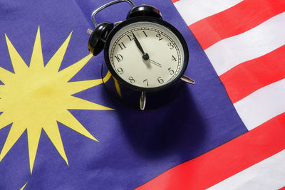 High angle view of alarm clock on malaysian flag