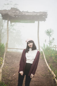 Portrait of young woman standing against trees