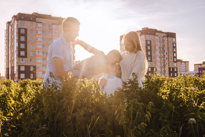 People on plants by buildings against sky