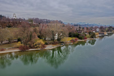 Reflection of trees in lake against sky in city