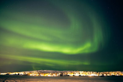 Scenic view of illuminated landscape against sky at night during winter