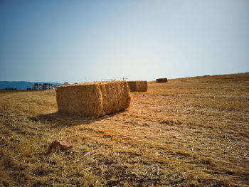 Hay bales on field against clear sky