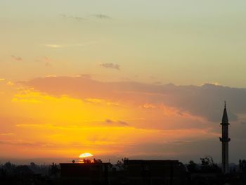 Silhouette of city against sky during sunset