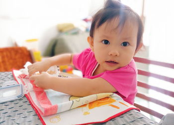 Portrait of cute baby girl on bed at home