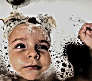Close-up portrait of boy with bubbles in bathroom
