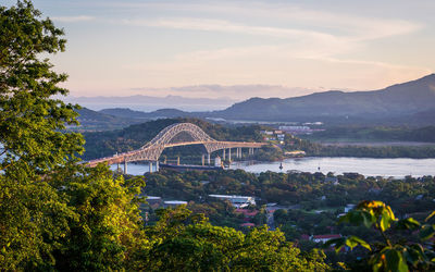 Scenic view of bay by bridge against sky