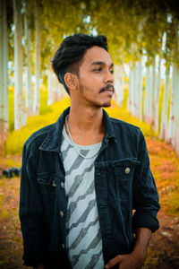 Young man looking away while standing outdoors