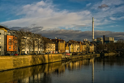 Buildings by river against sky in city