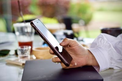 Close-up of person using mobile phone on table