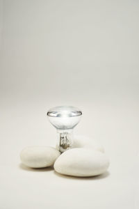 Close-up of stones and light bulb on white background