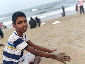 Portrait of boy playing with sand at beach