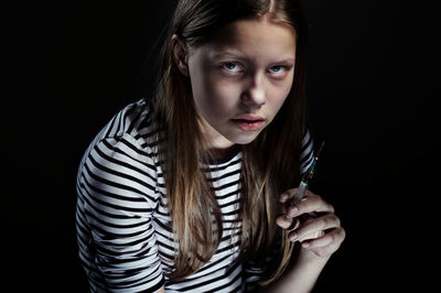 Close-up portrait of young woman against black background