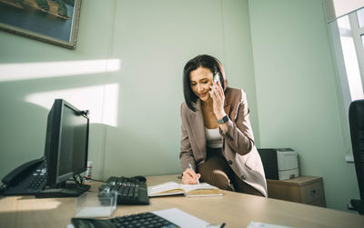 Smiling businesswoman using mobile phone in office. small business entrepreneur, smile, communicate