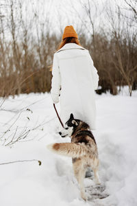 Rear view of woman standing on snow covered field