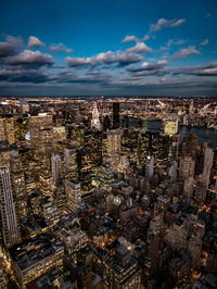 Chrysler building amidst illuminated cityscape against sky at dusk