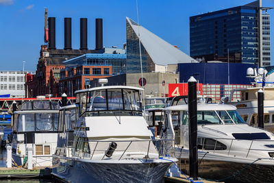 Sailboats moored at harbor against buildings in city