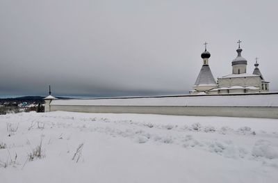 Cross on snow covered building against sky