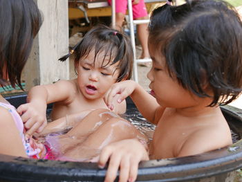 Cute girls enjoying bathing in bucket