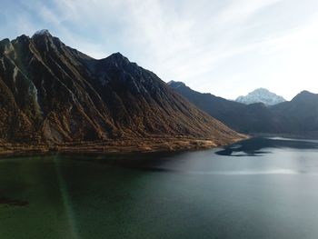 Scenic view of sea by mountains against sky