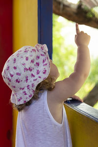 Girl pointing by window at home