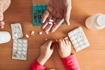 Grandchild helping grandfather to organize medication into pill dispenser. healthcare concept