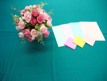 High angle view of roses in vase by papers on fabric