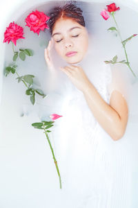 Close-up of woman with pink flowers against blurred background