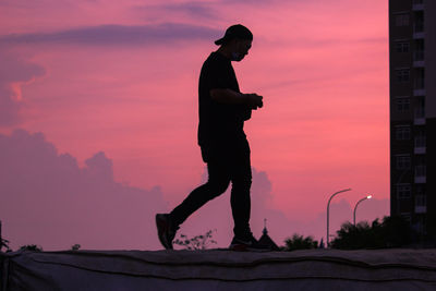 Rear view of silhouette man standing against sky during sunset